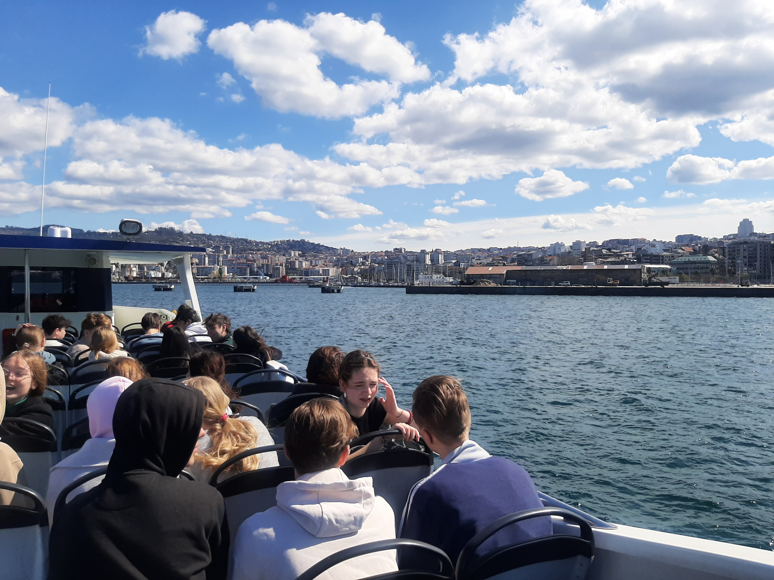 Schülerinnen und Schüler auf dem Oberdeck der Fähre von Vigo nach Cangas mit Blick auf die Stadt