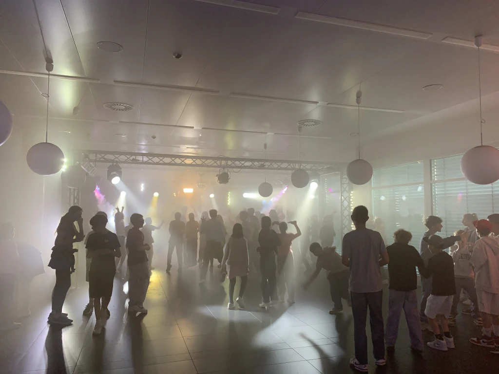 Tanzende Schülerinnen und Schüler im Scheinwerferlicht auf der Orientierungsstufenparty
